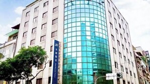 A multi-story building with a curved glass facade and a blue sign indicating a hotel. - Meworld Hotel-Sanchong (New Taipei City)