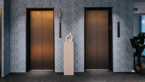 A modern elevator with a textured wall and a minimalist design. - Meworld Hotel-Sanchong (New Taipei City)