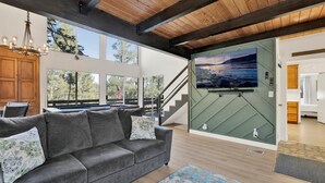 A modern living room with a gray sofa, a large painting, and a pool table. - Round Rock Lodge at Big Bear | Boulder Bay Modern Retreat w/ Pool Table | Minutes to Activities (Big Bear Lake)