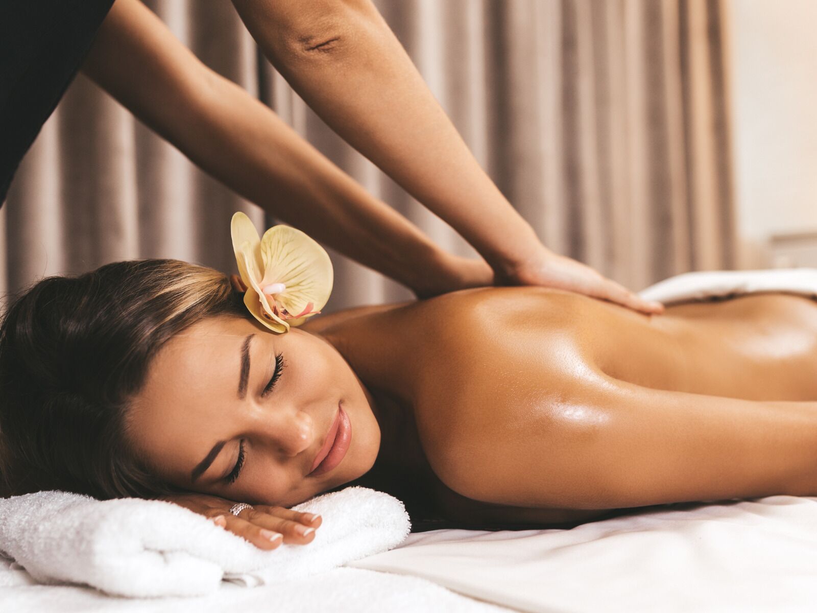 Uma pessoa recebendo massagem nas costas em uma toalha branca.