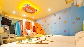 A child's bedroom with a bed, a play area with a slide, and a wall decorated with animal stickers. - Toyfun Hotel (Yilan)