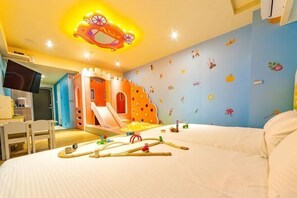 A child's bedroom with a bed, a play area with a slide, and a wall decorated with animal stickers. - Toyfun Hotel (Yilan)
