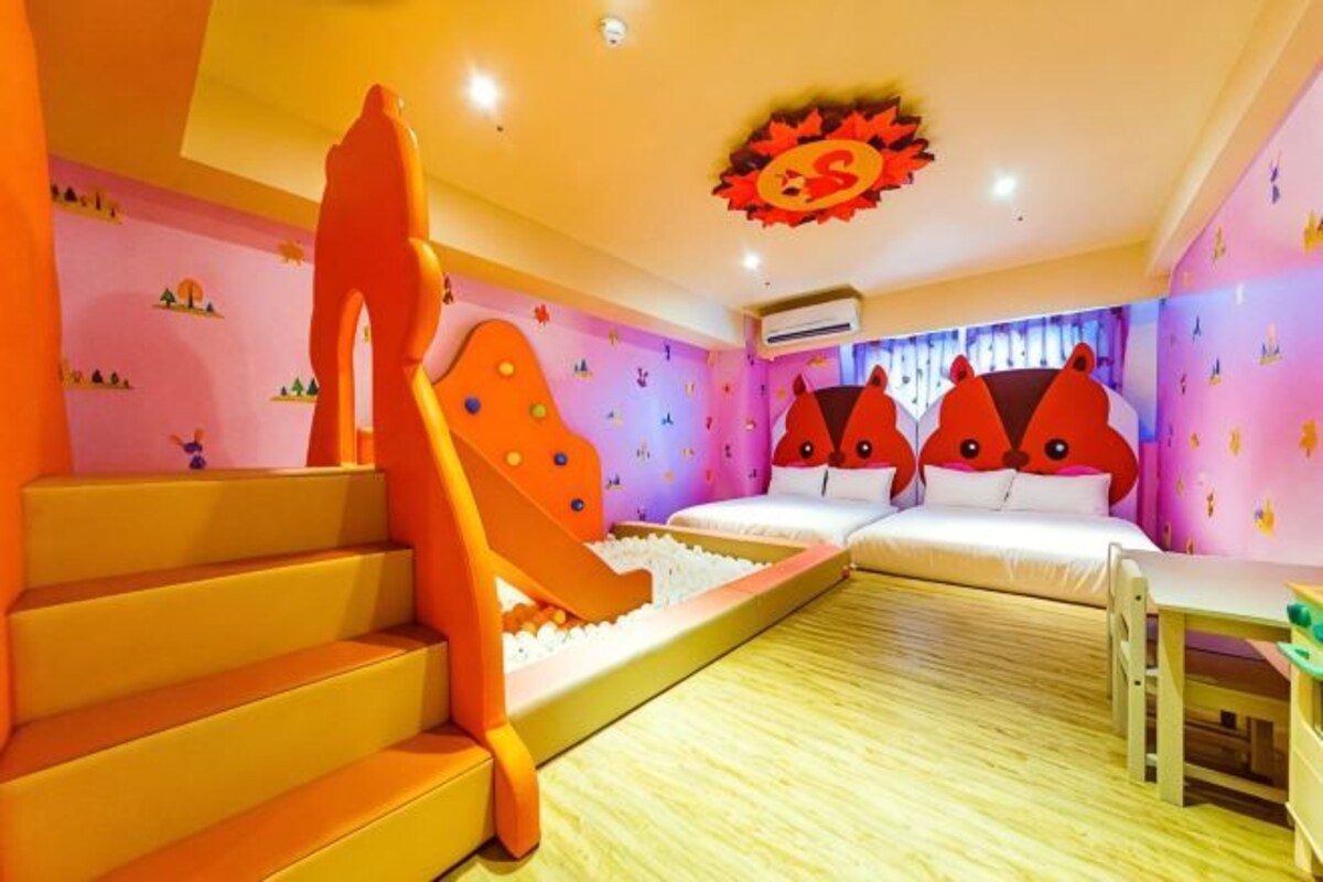 A room with a bed, a desk, a chair, and a staircase.