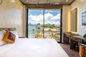 Une chambre d’hôtel avec un grand lit, un balcon avec des chaises, un bureau et un grand miroir.