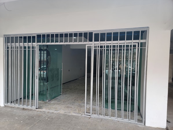 A gated entrance with a metal gate and glass doors, leading to a hallway with a tiled floor.