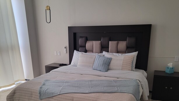 A bedroom with a large bed, a dark headboard, and a stone-patterned floor. - Your perfect stay awaits you in the heart of Uruapan! Olivier Suites & Lofts (Uruapan)