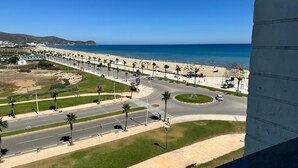 Eine Küstenstraße mit Palmen, einem Strand und blauem Himmel.