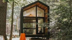 Una cabaña moderna con ventanas amplias, rodeada de árboles.