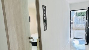 Un pasillo con un cartel que dice 'WELCOME', una puerta y vistas al exterior.