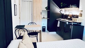A compact hotel room with a bed, a small kitchenette, a dining area, and a bathroom. - Picasso Escape; Close to Parque de los Novios. (Santa Marta)