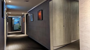 A hallway with a wooden floor, a large wardrobe, and framed pictures on the wall. - Pure meworld hotel (Taipei)