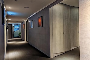 A hallway with a wooden floor, a large wardrobe, and framed pictures on the wall. - Pure meworld hotel (Taipei)