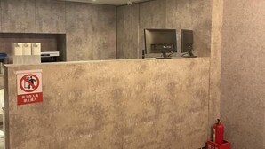 A reception area with a grey textured wall, a no entry sign, a fire extinguisher, and a counter with a computer monitor. - Pure meworld hotel (Taipei)
