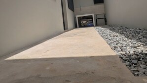 Un edificio moderno con tragaluces, un camino de hormigón y una zona de grava.