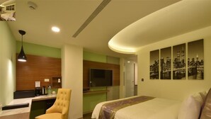 A hotel room with a bed, a desk, a chair, a TV, and a cityscape artwork on the wall. - Good Hotel (Kaohsiung)
