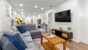 A modern living room with a grey sofa, wooden coffee table, and a black TV stand. - Central 3-bedroom House with a Yard and Free Parking, Near Downtown (San Diego)