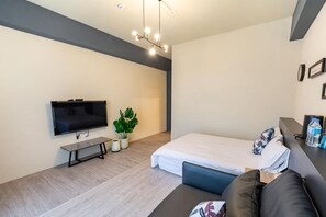 Ein modernes Zimmer mit Bett, Fernseher, einer Sitzbank und einer Pflanze.
