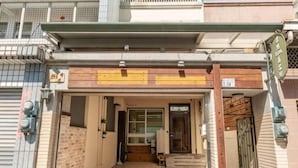 A building entrance with a wooden door, a small step leading up, and a metal gate on the right. - Senshe B&B (Taitung)