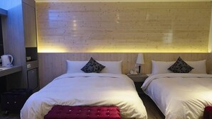 A hotel room with two beds, a wooden headboard, a desk with a chair, and a red bench. - Penghu Royal Hotel (Penghu)