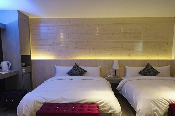 A hotel room with two beds, a wooden headboard, a desk with a chair, and a red bench. - Penghu Royal Hotel (Penghu)