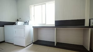 A laundry room with a washing machine, a sink, and a window. - Penghu Royal Hotel (Penghu)