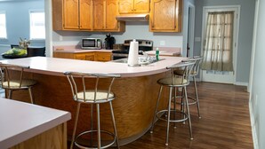 A kitchen with wooden cabinets, a stainless steel sink, and a large island with bar stools. - Bright & Comfortable 3-bedroom Retreat in Cottondale. Only 6 miles from Campus! (Cottondale)