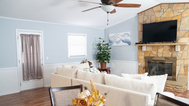 A living room with a stone fireplace, a flat-screen TV mounted above it, a sofa, and a dining table with a vase of flowers. - Bright & Comfortable 3-bedroom Retreat in Cottondale. Only 6 miles from Campus! (Cottondale)