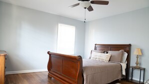 A bedroom with a wooden bed, a ceiling fan, a nightstand, and a window with blinds. - Bright & Comfortable 3-bedroom Retreat in Cottondale. Only 6 miles from Campus! (Cottondale)