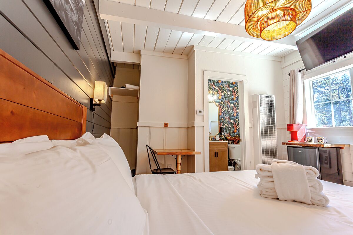Una habitación de hotel con cama, escritorio, silla, televisor y ventana.