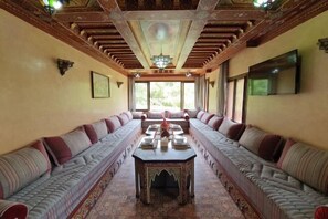 Une longue pièce avec une table au centre et des canapés le long des murs.