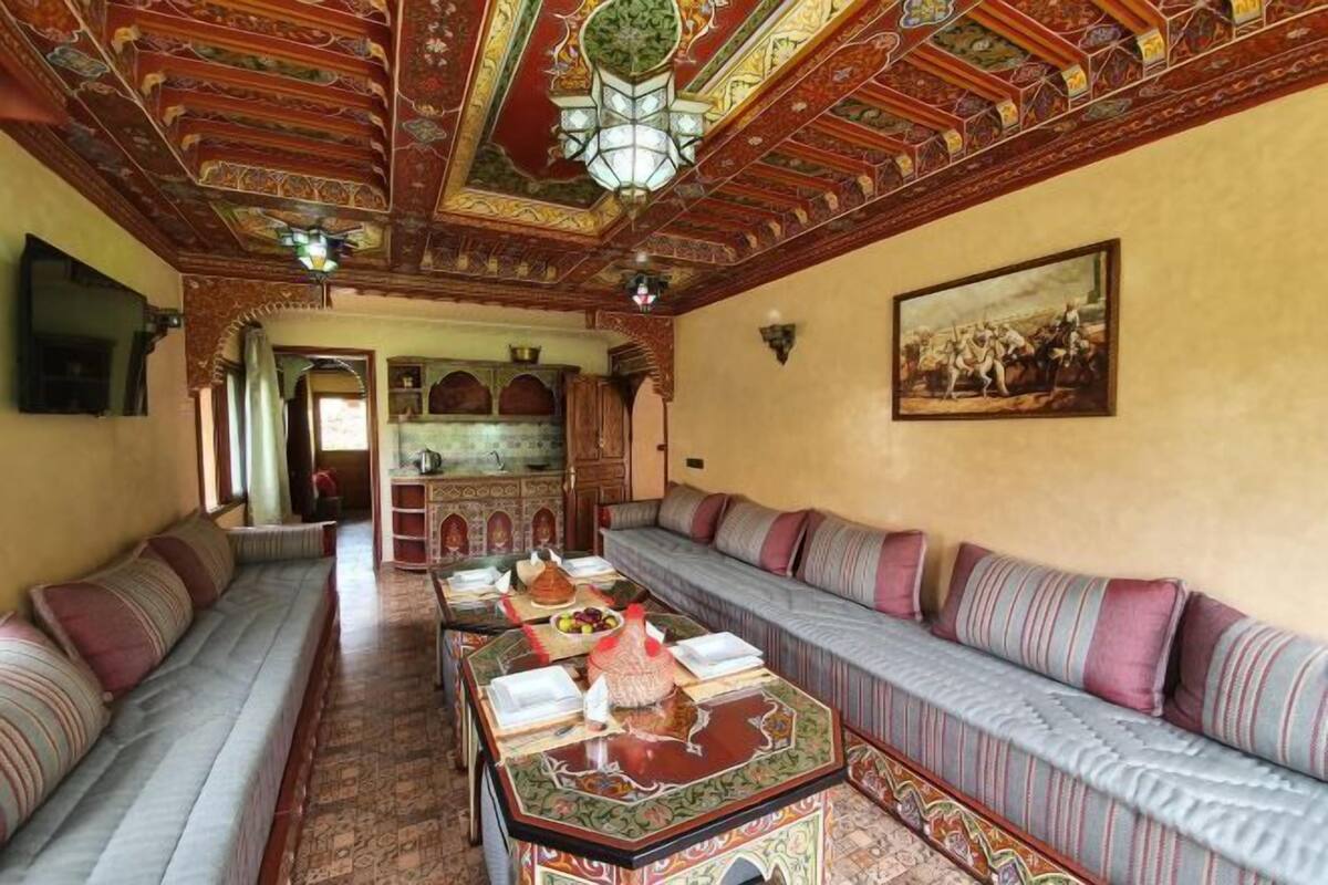 Una camera tradizionale con una zona salotto, un tavolo da pranzo con un teiera e un lampadario.