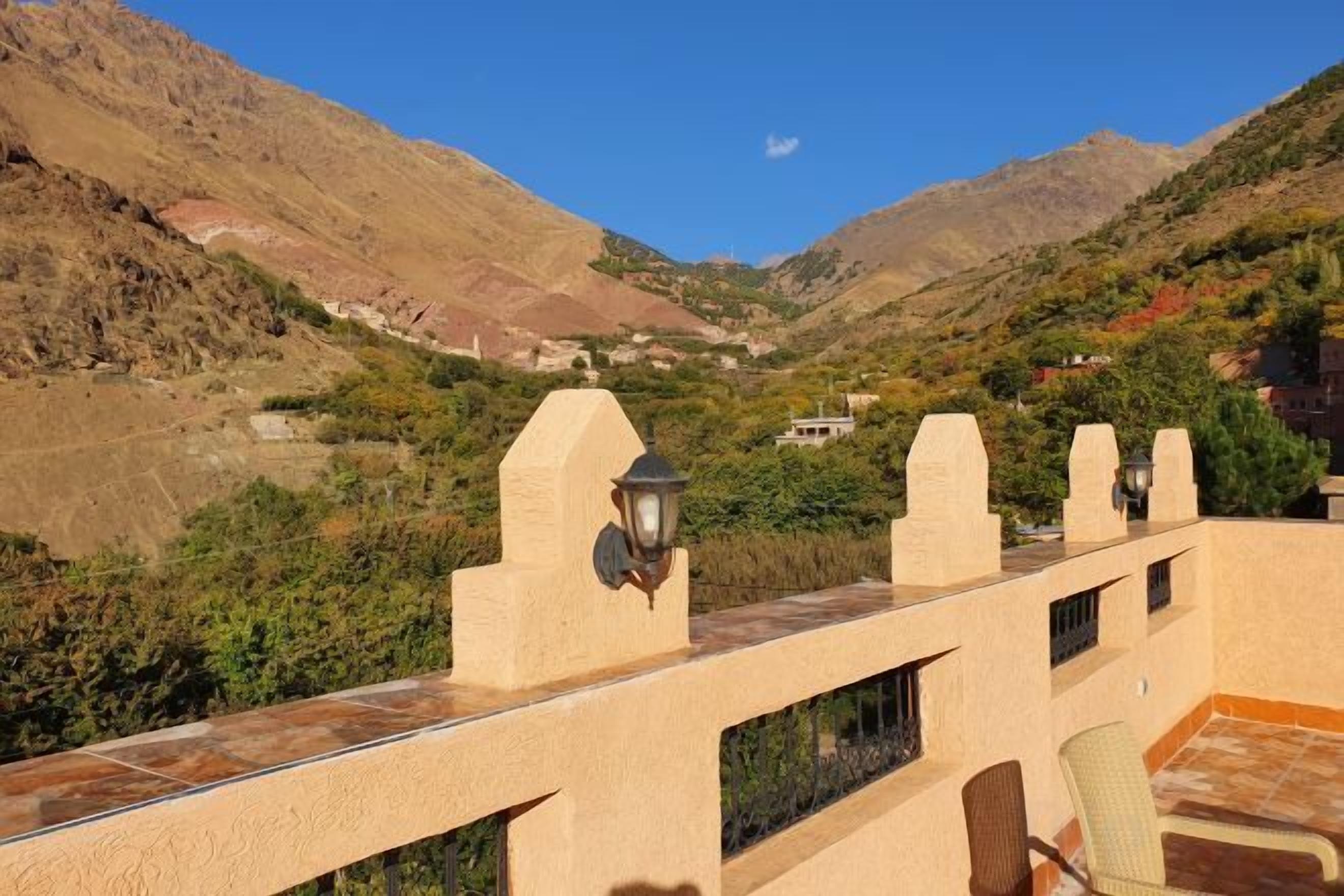 A terrace with a view of a mountainous landscape, a lamp, and a chair.