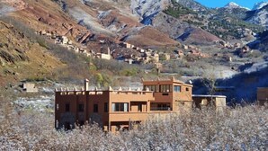 Un village de montagne aux bâtiments traditionnels, avec une structure moderne imposante qui se détache au premier plan.