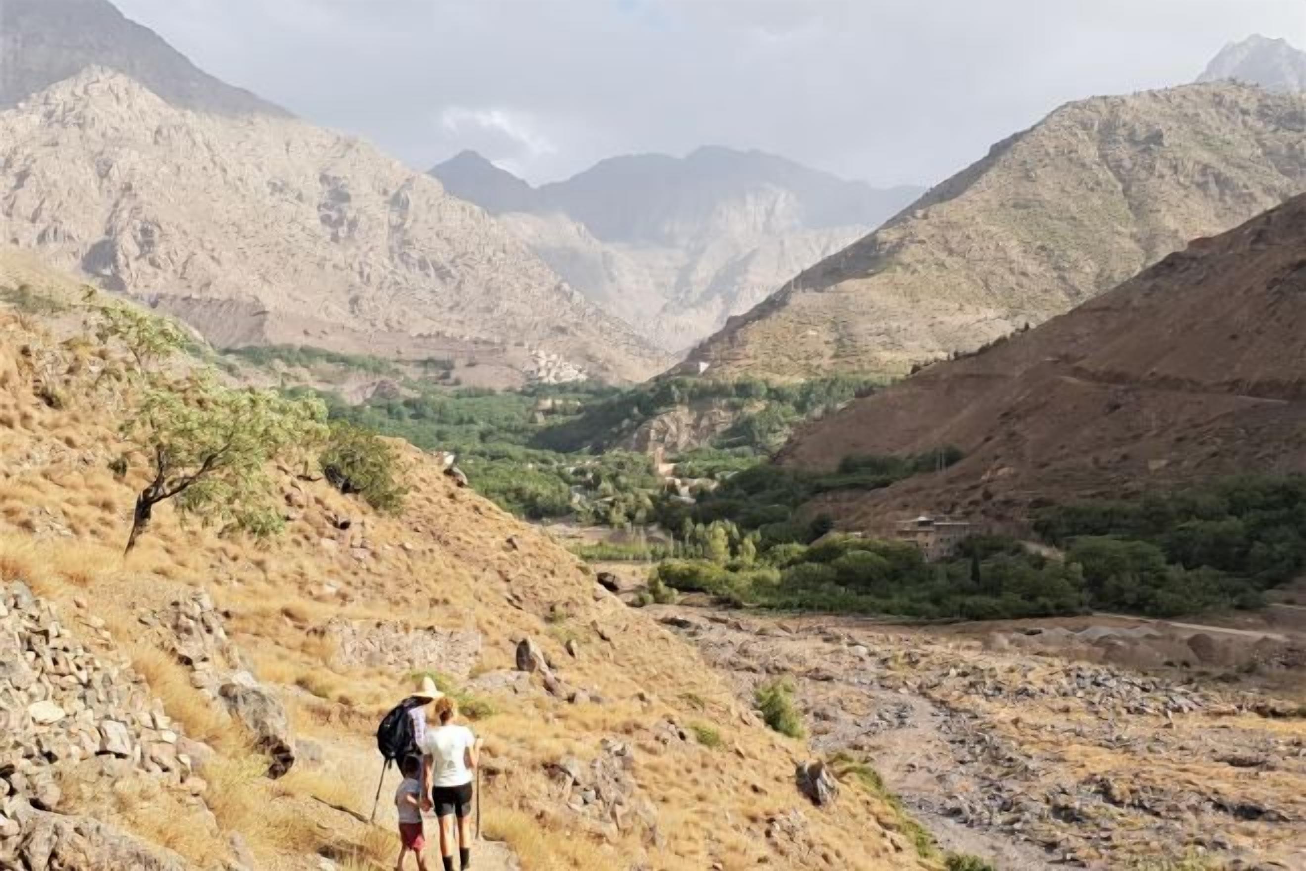 A mountainous landscape with a valley and a person hiking.
