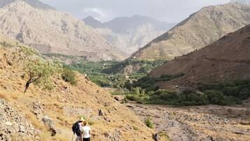A mountainous landscape with a valley and a person hiking.