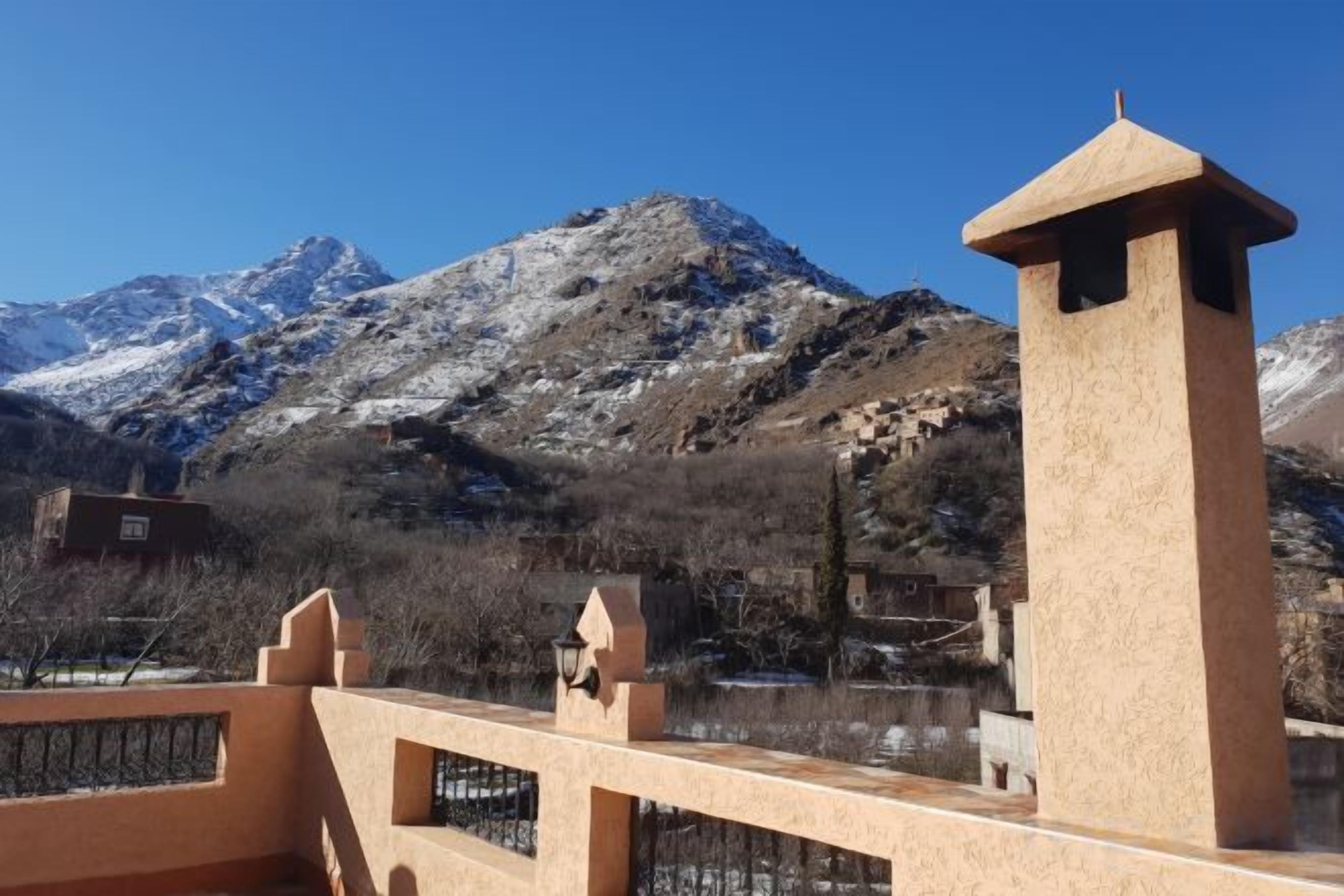 A mountain landscape with a clear sky, a stone tower, and a fence.