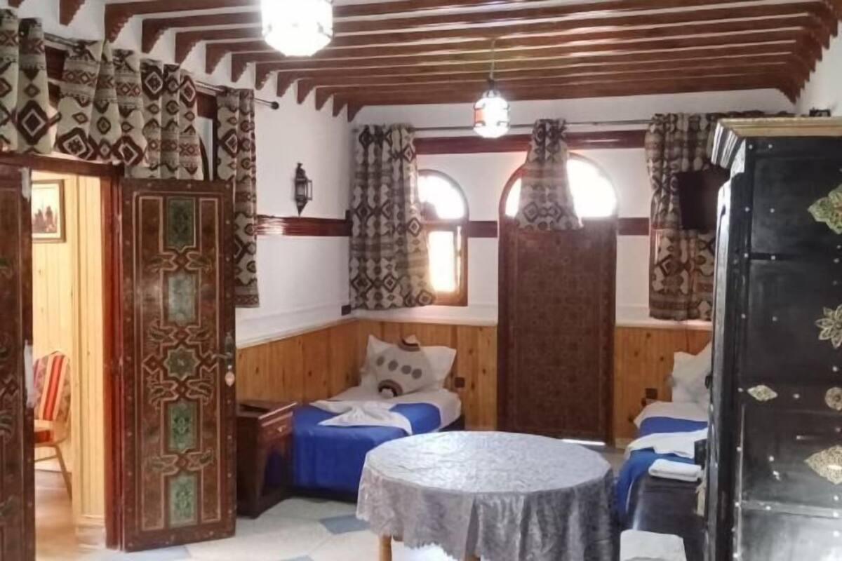 Una stanza con un letto, un tavolo rotondo e un'armadio.