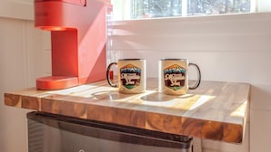 Een keuken met een koffiezetapparaat, twee mokken met een berglogo en een vaatwasser.