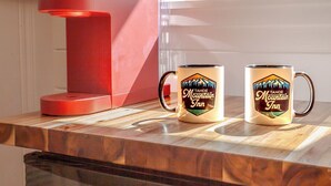 Une machine à café rouge et deux tasses ornées du logo « Tahoe Mountain Inn » sont posées sur un plan de travail de cuisine.