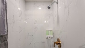 A bathroom with white marble tiles, a showerhead, and a control panel with three buttons. - Tahoe Mountain Inn #29 (SOUTH LAKE TAHOE)