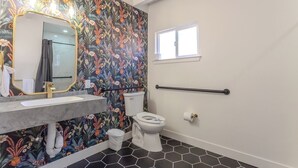 Een badkamer met bloemenbehang, een moderne wastafel, een toilet en een raam.