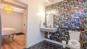 Een badkamer met bloemen behang, een witte wastafel, een spiegel en een toilet.