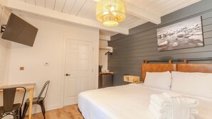 Een hotelkamer met een bed, een bureau met stoel, een televisie aan de muur en een schilderij.