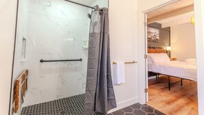Een moderne badkamer met een douchecabine van glas, een handdoekrek en een bedieningspaneel voor de douche.