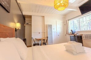 A hotel room with a bed, a table with chairs, a TV, and a window with a view of trees. - Tahoe Mountain Inn #33 (SOUTH LAKE TAHOE)