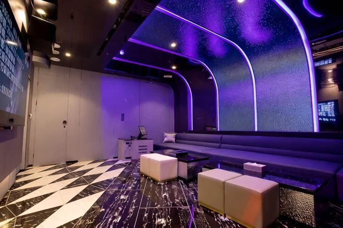 A modern room with a checkered floor, a sofa, a desk, and a wall with a digital display.