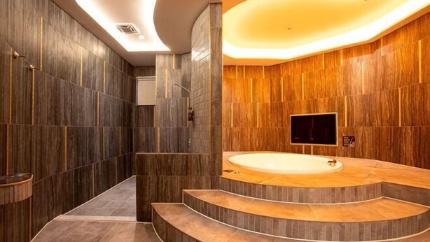A modern bathroom with a curved sink, a large mirror, and a TV mounted on the wall. - I Will Motel (Hsinchu County)