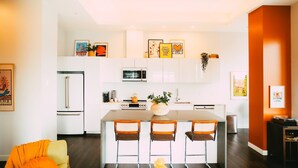 A modern kitchen with white cabinets, a central island with bar stools, and a refrigerator. - *Free Parking* Cozy 2br/2ba Penthouse DT Halifax! (Halifax)