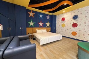 A bedroom with a bed, a blue sofa, and a wall decorated with stars and circular patterns.
