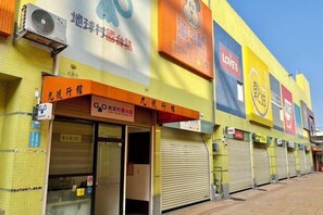 A row of closed shops with metal shutters, a clear sky, and a yellow building facade. - No9 Hotel (Changhua)